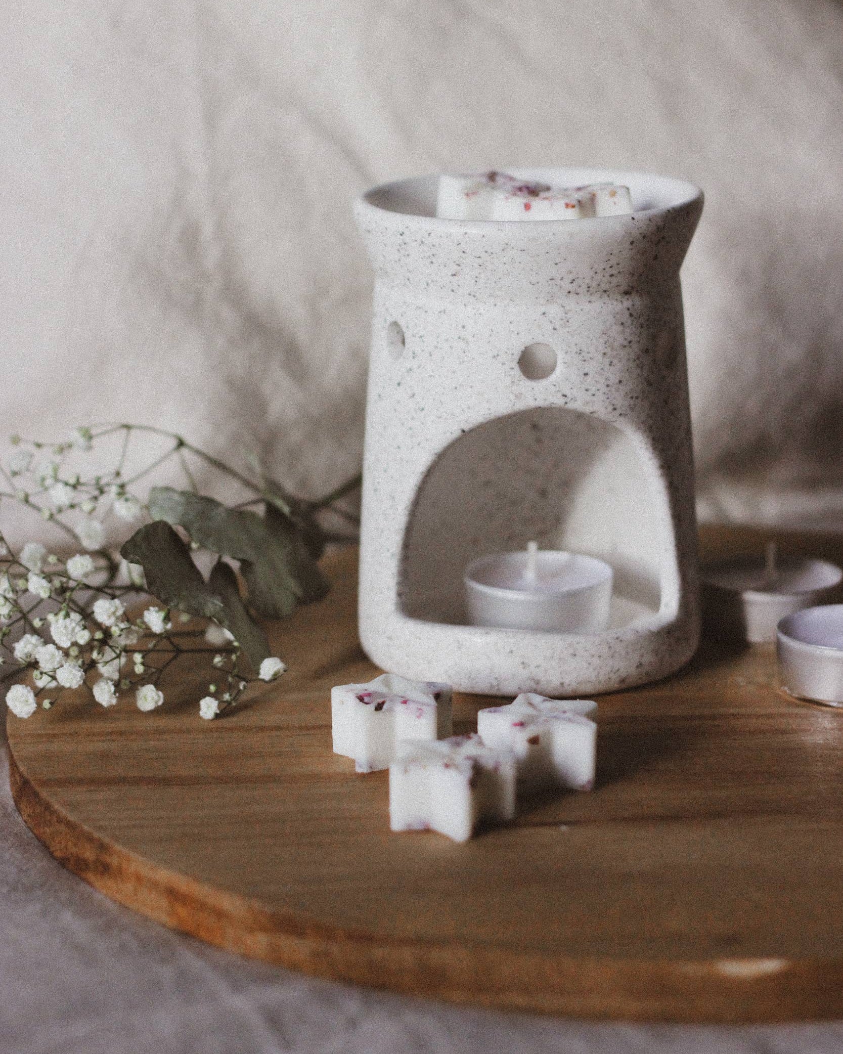 White ceramic wax warmer with small containers on a wooden surface