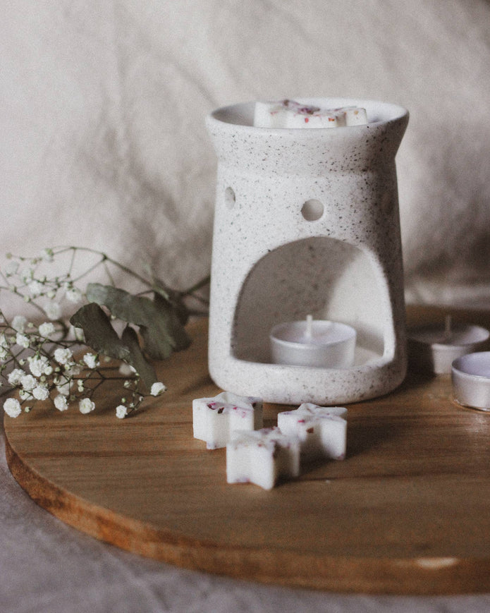 White ceramic wax warmer with small containers on a wooden surface