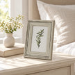 Small Alba wooden photo frame on a light bedside table beside white flowers