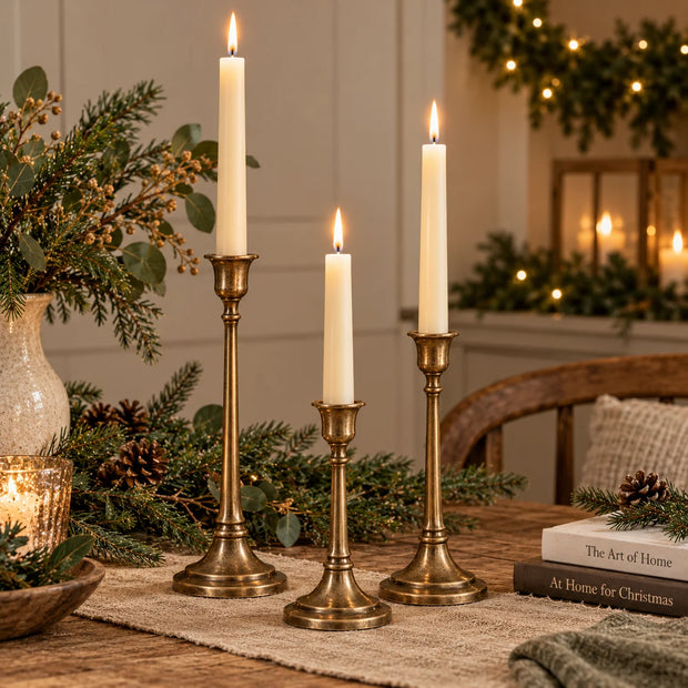 Three antique brass effect taper candlesticks in different sizes, perfect for elegant home decor and festive table settings.