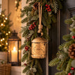 Single antique gold hanging cow bell on jute rope in Christmas greenery beside a front door