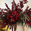 Burgundy gypsophila flower clusters with evergreen foliage and ribbon styling.