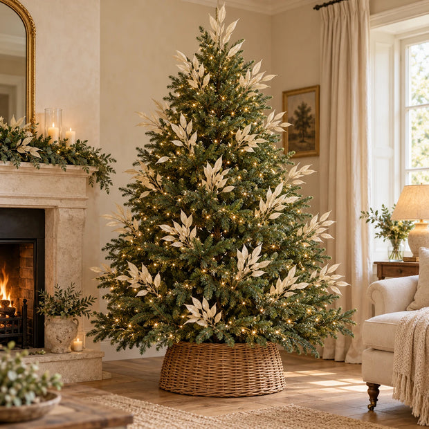 Multiple artificial cream leaf stems arranged through a green Christmas tree with lights, before adding baubles.