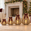 Four graduated bamboo LED lanterns with burgundy bows beside a Christmas fireplace; each sold individually