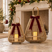 Two bamboo lanterns with LED candles and burgundy bows beside a Christmas fireplace; bows are styling props