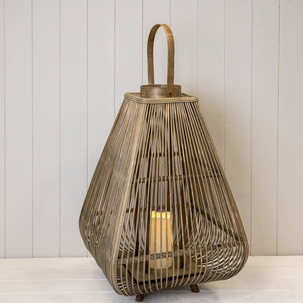 Angled view of a bamboo lantern showing its tapered slats, rounded base, arched handle and LED candle