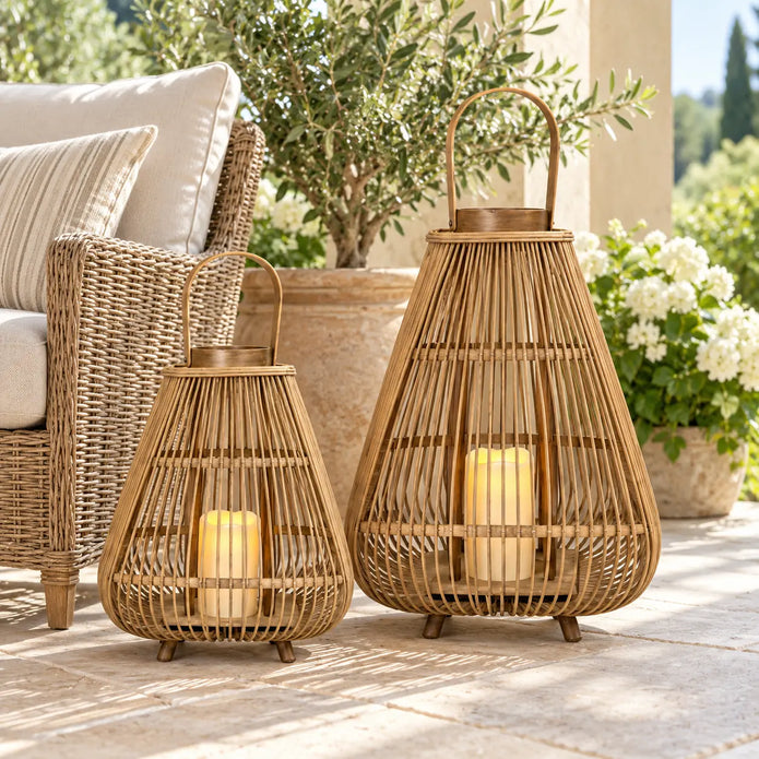 Two bamboo lanterns with LED candles beside a woven chair on a sheltered summer patio