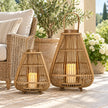 Two bamboo lanterns with LED candles beside a woven chair on a sheltered summer patio