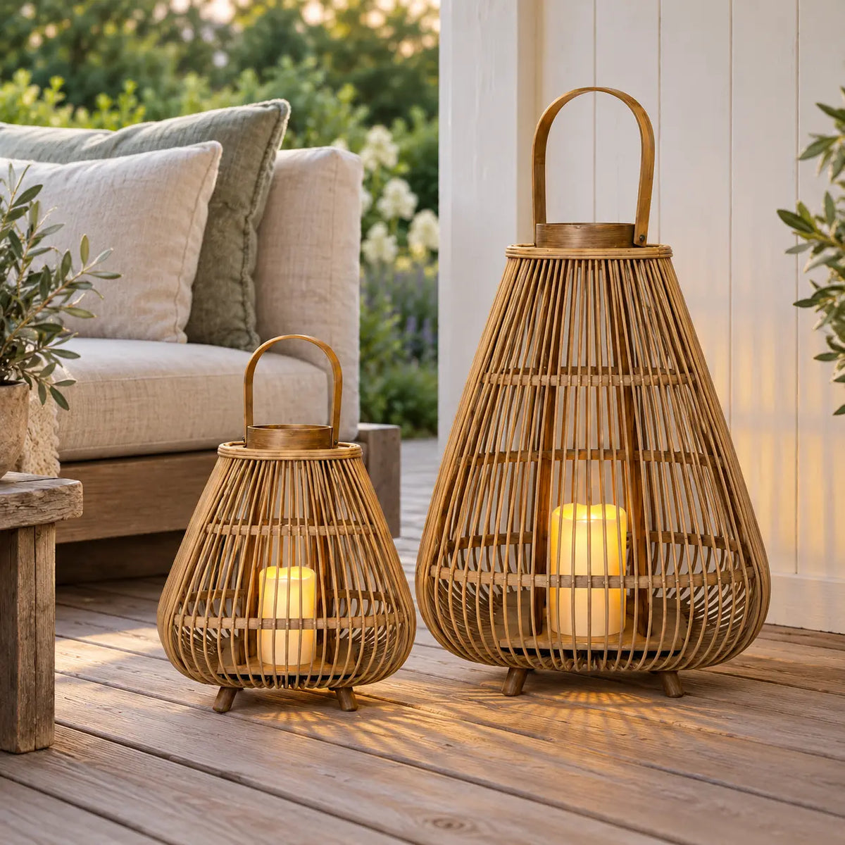 Two bamboo LED candle lanterns on a wooden veranda beside a woven sofa