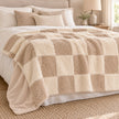 Riva Home beige and cream fur boucle check blanket throw draped on a bedroom bed