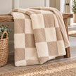 Beige and cream fur boucle check blanket throw by Riva Home draped over an oak bench