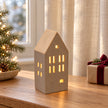 Beige ribbed LED house on an oak table with a neutral Christmas gift