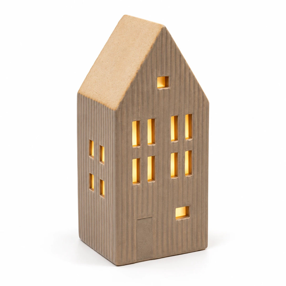 Close studio view of the illuminated beige ceramic house showing ribbed walls and sand roof
