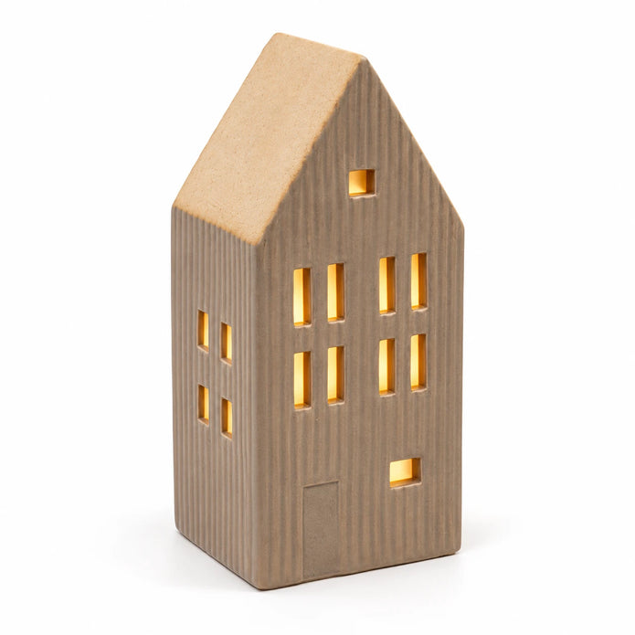 Close studio view of the illuminated beige ceramic house showing ribbed walls and sand roof