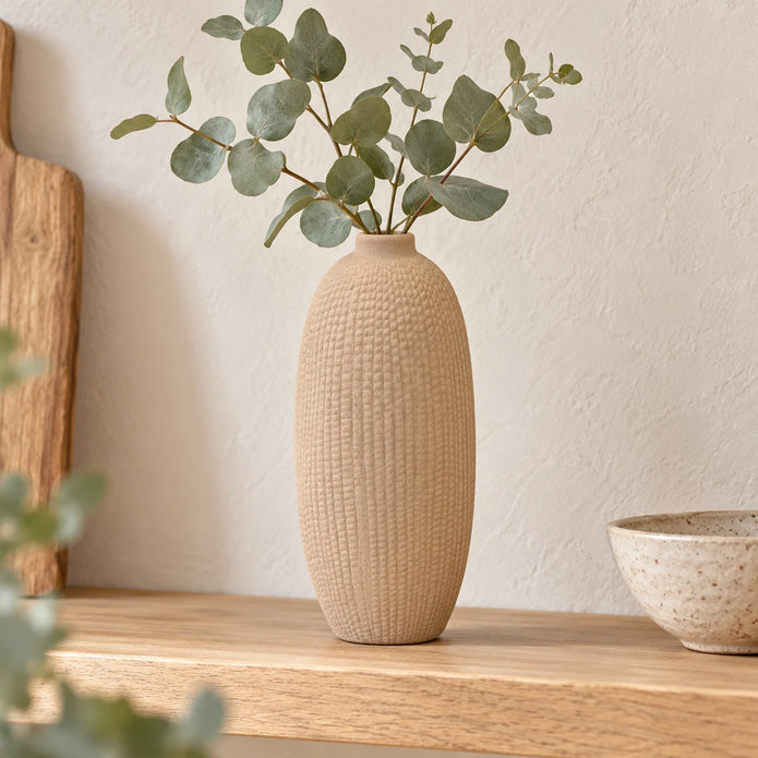 Beige textured vase styled with eucalyptus on a wooden kitchen shelf