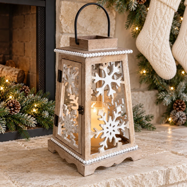 White snowflake candle lantern styled on a cream hearth with Christmas greenery