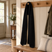 Black cable knit scarf hanging on an oak peg rail in a country hallway