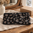 Black fluffy leopard print headband styled on an oak dressing table