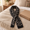 Black fluffy leopard print pull-through scarf styled on an oatmeal throw