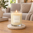Heaven Scent Black Oud Medium Candle lit on a stone coaster in a living room