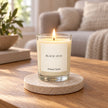 Heaven Scent Black Oud Small Candle lit on a stone coaster in a living room