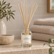 Black Pomegranate Reed Diffuser styled on a stone bathroom shelf with reeds inserted.