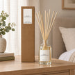 Black Pomegranate Reed Diffuser with reeds inserted beside its matching kraft gift box.