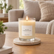 Heaven Scent Black Pomegranate Medium Candle lit on a stone coaster in a living room
