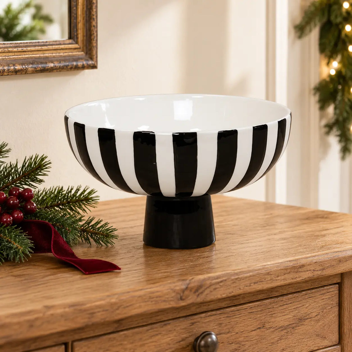 Black and white striped ceramic footed bowl on an oak console with Christmas greenery