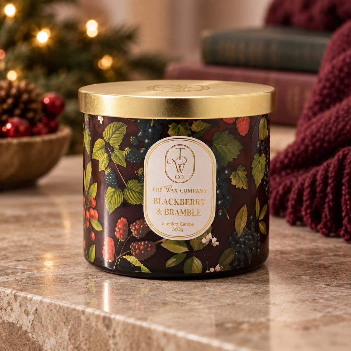 Blackberry and Bramble botanical candle with gold lid, on a stone coffee table