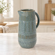 Medium 27cm blue ceramic jug with mottled glaze and textured bands, kitchen view.