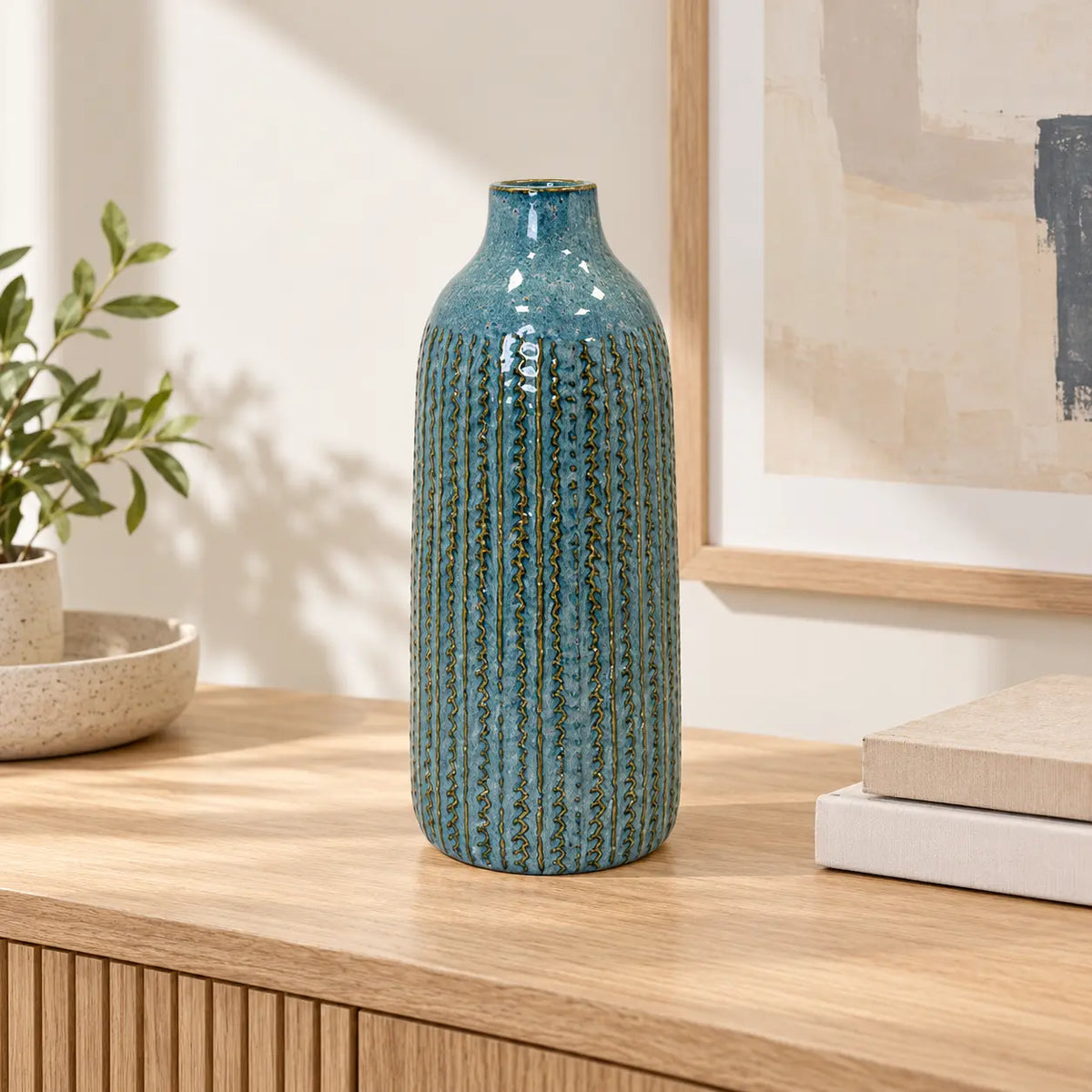 Large blue ceramic vase on an oak console in a bright neutral interior.