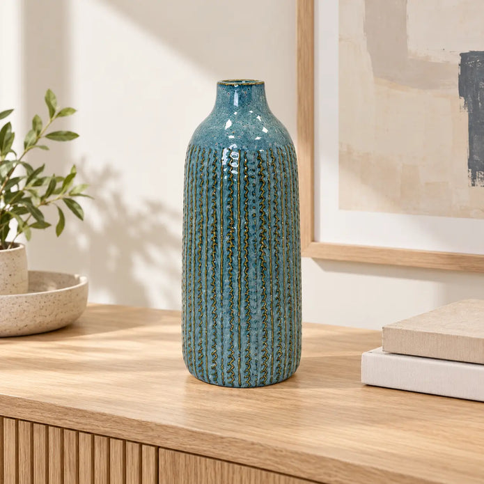 Large blue ceramic vase on an oak console in a bright neutral interior.