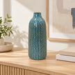 Large blue ceramic vase on an oak console in a bright neutral interior.
