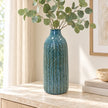 Large blue ceramic vase styled with eucalyptus on a light stone sideboard.