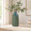 Medium blue ceramic vase styled with eucalyptus on a light stone sideboard.