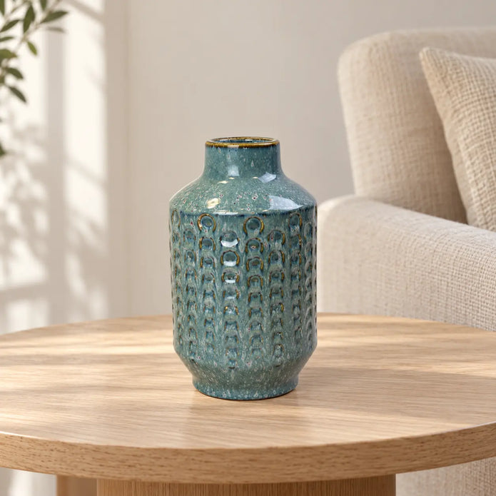 Small blue ceramic vase on an oak side table in a neutral living room.