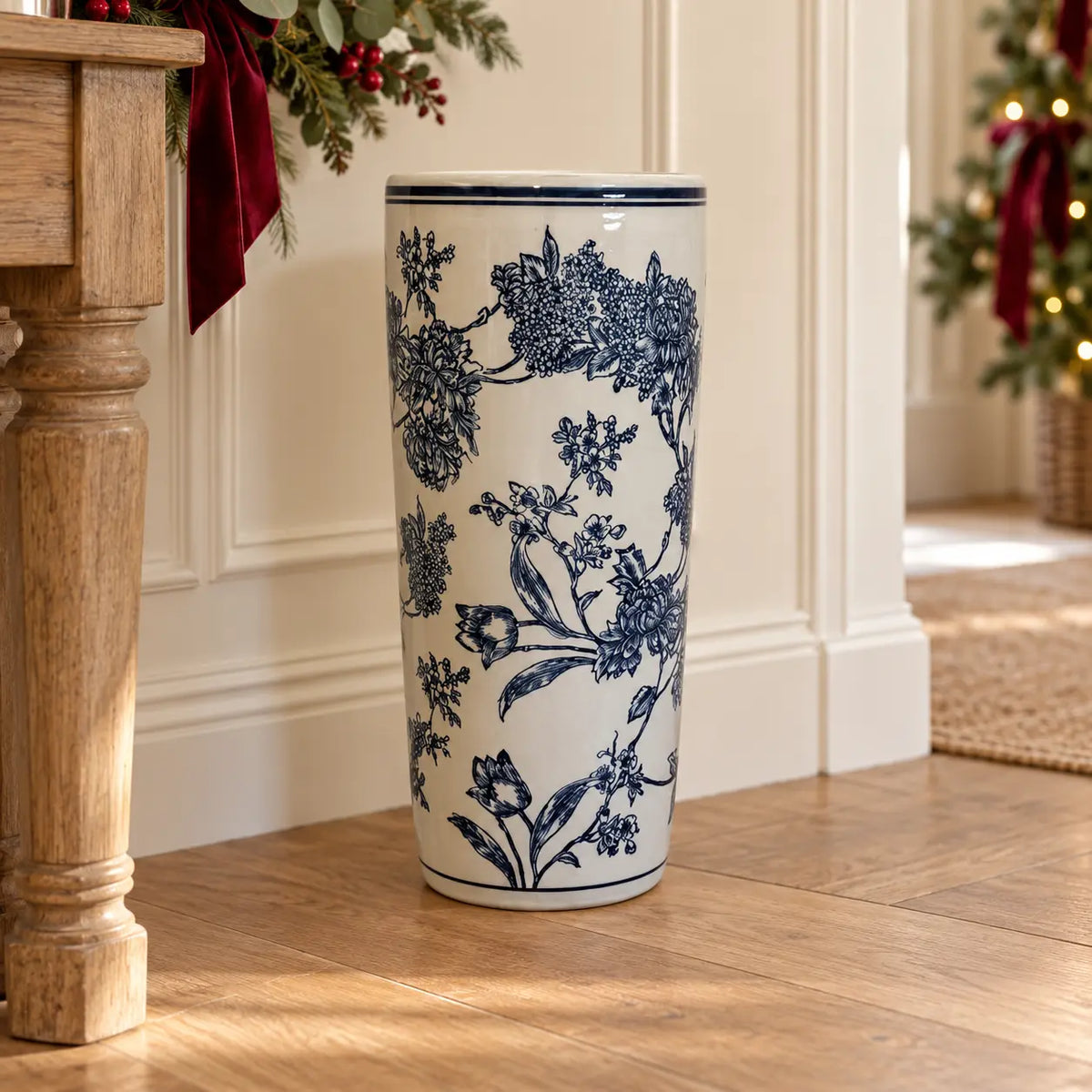 Blue and white magnolia umbrella stand beside an oak console with Christmas greenery