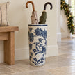 Vintage blue and white floral umbrella stand holding two umbrellas in a hallway