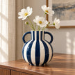 Blue and white striped globe vase styled with white cosmos stems on a walnut sideboard