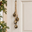 Small cowbell hanging garland on a cream interior door with Christmas greenery