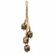 Four antiqued brass-toned cowbells on a rope hanging garland, white studio background
