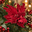 Close-up of the burgundy Style 2 flower with textured petals among Christmas greenery.
