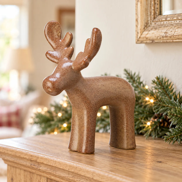 Brown Ceramic Reindeer — Single reindeer on oak mantel with fir garland in distant background