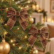 Two small brown checked tweed bows styled on a lit Christmas tree