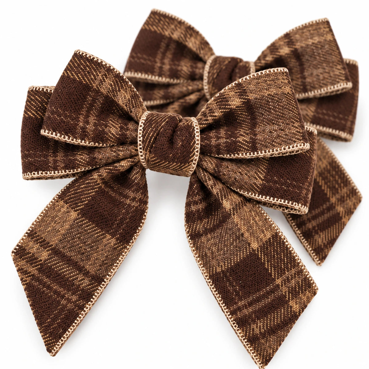 Close-up of two brown checked tweed bows showing stitched edging and woven texture