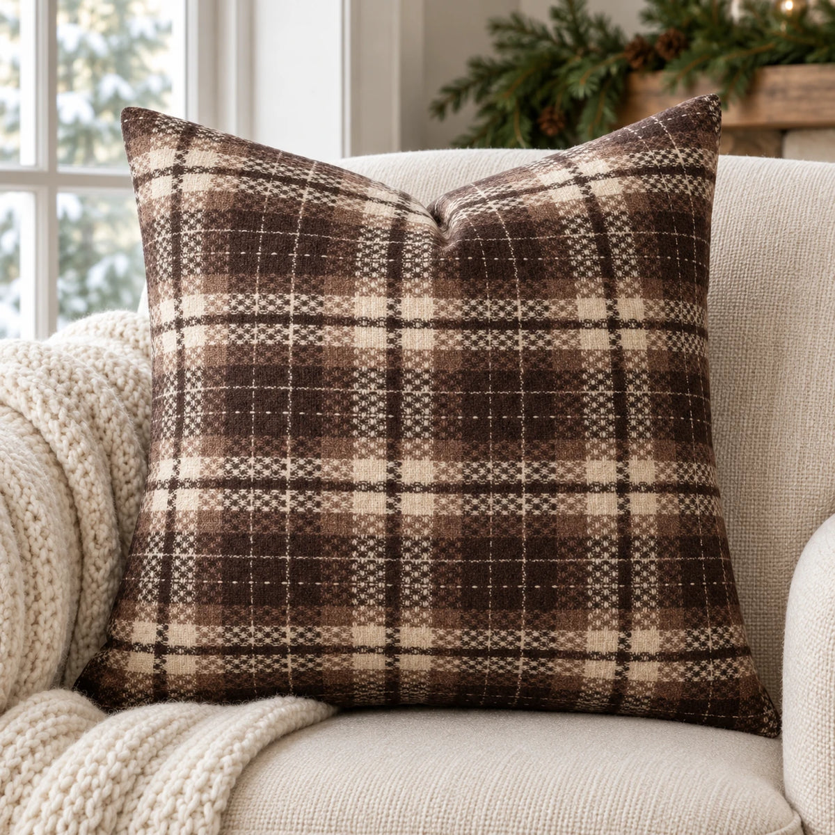 Brown and cream tartan cushion cover on an oatmeal armchair with a knitted throw