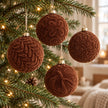 Brown velvet Christmas bauble from Starlight Express hanging on a decorated Christmas tree.