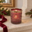Burgundy dotted glass tealight holder with distressed gold rim, styled with a candle on a stone mantel.