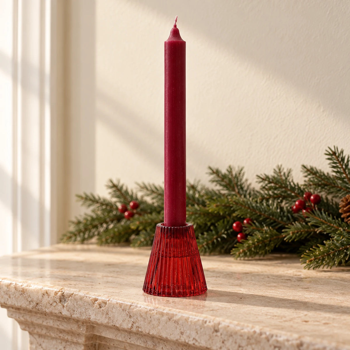 Burgundy glass dinner candle holder with red taper on a Christmas mantel